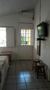 Pokój z telewizorem na ścianie i stołem w obiekcie Flat Pico Vulcanico w mieście Fernando de Noronha