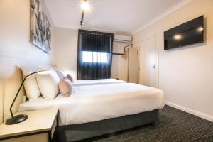 Pokój hotelowy z łóżkiem i biurkiem w obiekcie Nightcap at Hendon Hotel w mieście Adelaide