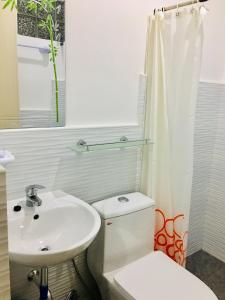 ein weißes Bad mit einem Waschbecken und einem WC in der Unterkunft Pisces Tourist Inn - Port Barton in San Vicente
