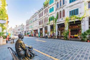 a statue of a man sitting on a bench on a street at Haikou Meilan District · Xixili Locals Apartment 00175140 in Haikou