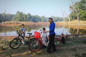 a woman standing next to a bike with a boy at Tiger Corner Inn Homestay in Sauraha