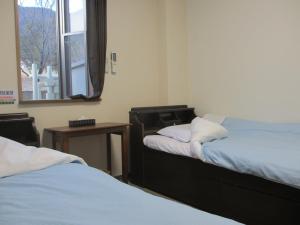 Cette chambre comprend 2 lits, une table et une fenêtre. dans l'établissement Fujibou Hotel, à Fujikawaguchiko