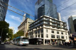 un autobús pasando un edificio en una calle de la ciudad en City Edge on Elizabeth Apartment Hotel, en Melbourne