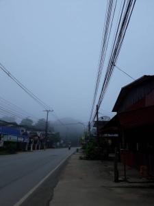 eine leere Straße mit einer Person, die mit einem Motorrad die Straße hinunterfährt in der Unterkunft ซอยห้า โฮมสเตย์ เชียงคาน in Chiang Khan