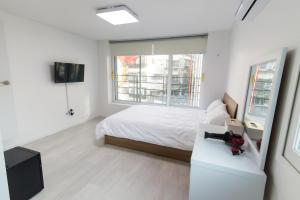 a white bedroom with a bed and a window at Kpop Haus in Seoul