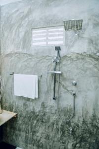 ein Bad mit einer Dusche und einem weißen Handtuch in der Unterkunft More Joy in Matara