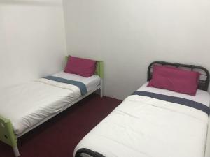 two beds in a small room with red and purple pillows at Seri Manjung Homestay Wazer Residence in Lumut