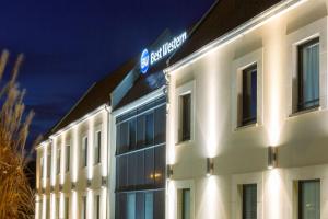 a large white building with a blue sign on it at Hotel Best Western La Mare Ô Poissons in Ouistreham