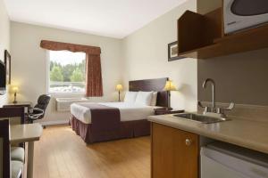 een hotelkamer met een bed en een wastafel bij Days Inn by Wyndham Chetwynd in Chetwynd +36 foto's