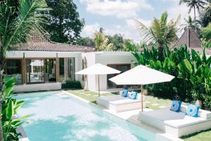 eine Villa mit einem Pool und 2 Sonnenschirmen in der Unterkunft The Apartments Ubud in Ubud