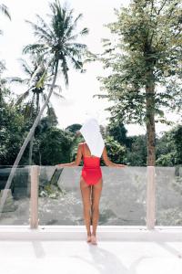 a woman in a red bikini with a white hat at The Apartments Ubud in Ubud