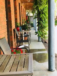 un patio al aire libre con mesas, sillas y plantas en La Cochon Rose Motel, en Saint Arnaud