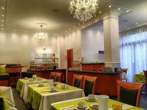 ein Restaurant mit 2 Tischen, Stühlen und Kronleuchtern in der Unterkunft Hotel Hansa in Offenbach
