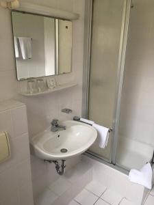 a white bathroom with a sink and a shower at Hotel Papp-Mühle in Zersen