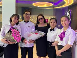 a group of people posing for a picture with flowers at Ha Noi Hotel near Tan Son Nhat International Airport in Ho Chi Minh City