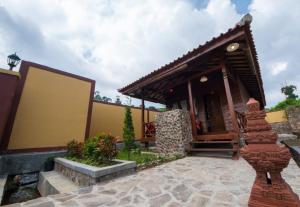 una casa con portico e un edificio di Puri Sakanti Nature Family Resort a Ciwidey