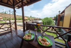 a table with two plates of food on a balcony at Puri Sakanti Nature Family Resort in Ciwidey