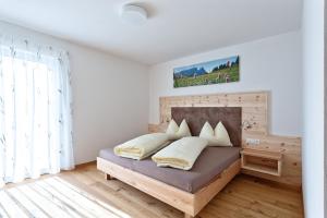 Schlafzimmer mit einem Bett mit einem Kopfteil aus Holz in der Unterkunft Tschörlerhof in Barbian