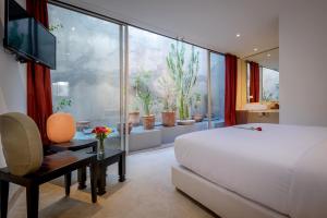 ein Schlafzimmer mit einem Bett und einem großen Fenster mit Topfpflanzen in der Unterkunft Ryad Marrakech in Marrakesch