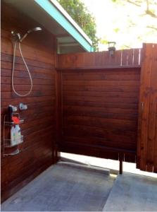 a bathroom with a wooden wall with a hose at Kalani Hawaii Private Lodging in Pupukea