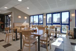 a dining room with tables and chairs and windows at B&B HOTEL Châlons-en-Champagne in Châlons-en-Champagne