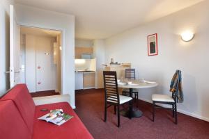 a living room with a red couch and a table at Vacancéole - Les Demeures Champenoises Confort in Épernay +9 photos