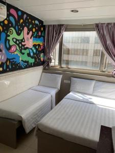 two beds in a room with a painting on the wall at 嘉應賓館HAKKAS GUEST House in Hong Kong