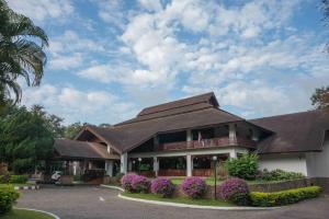 un edificio con techo marrón y flores púrpuras en The Imperial Mae Hong Son Resort, en Mae Hong Son