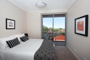 een slaapkamer met een bed en een groot raam bij The Junction Palais - Modern and Spacious 2BR Bondi Junction Apartment Close to Everything in Sydney