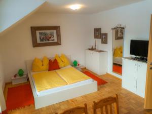 ein Schlafzimmer mit einem Bett mit gelben und orangefarbenen Kissen in der Unterkunft Ferienwohnung nahe Fuschlsee, Hof bei Salzburg in Hof bei Salzburg