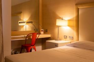 a bedroom with a bed and a desk with a red chair at Smy Bologna Centrale in Bologna