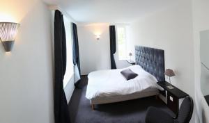a bedroom with a white bed and a window at La Demeure des 2 Trésors in La Bresse