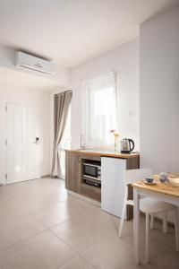 a white kitchen with a table and a counter at Island Guesthouse in Il-Gżira