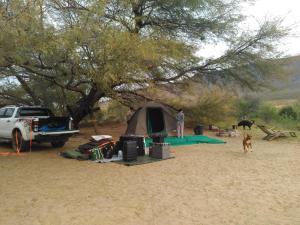 a man standing next to a tent under a tree at Enjo Nature Farm in Cederberg