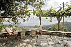 a stone table and chairs on a patio with mountains in the background at Pelion Belvedere - THE MANSION in Vyzitsa