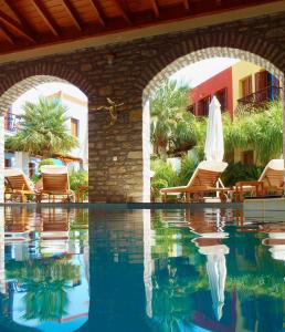 ein Pool in einem Resort mit Stühlen und einem Sonnenschirm in der Unterkunft Iapetos Village in Symi