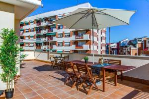 un patio con tavolo e ombrellone su un balcone di Feriapiso Apartments Palmer a Hospitalet de Llobregat