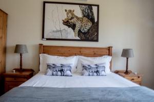 a bedroom with a bed with a cheetah painting on the wall at Cuckoo Ridge Country Retreat in Hazyview