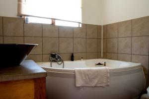 a white tub in a bathroom with a window at Cuckoo Ridge Country Retreat in Hazyview