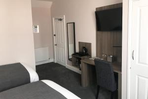 una camera d'albergo con scrivania e TV di Qudos a Salisbury