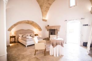 a white bedroom with a bed and a table at Corte di Bonifacio - Luxury Suites in Casarano