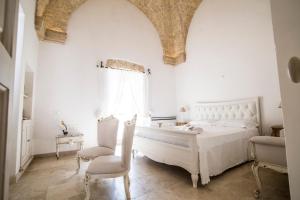 een witte slaapkamer met een bed en een stoel bij Corte di Bonifacio Typical Bed and Breakfast in Casarano