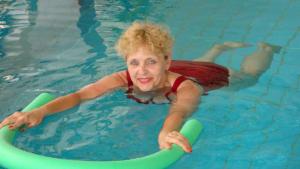 a woman in a swimming pool on a raft at Ferienhotel Münch in Neukirchen beim Heiligen Blut