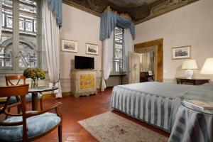 Palazzo Niccolini al Duomo Residenza D'Epoca في فلورنسا: غرفة نوم فيها سرير وتلفزيون