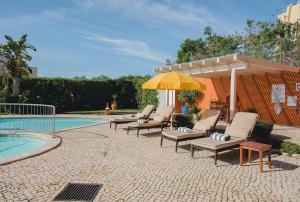 a group of chairs and an umbrella next to a pool at Villa Mar Azul in Lagos