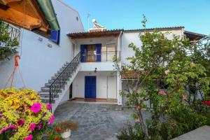 a white house with a blue door and stairs at Athina Apartments in Kato Korakiana