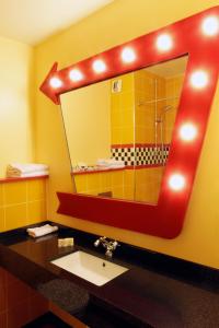 a bathroom with a sink and a mirror with a shower at Disney Hotel Santa Fe in Coupvray