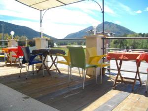 a deck with tables and chairs and a view of a mountain at Le Relais de l'Artuby in Séranon