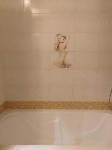 a bath tub with a picture of a woman on the wall at Apartments Galactika in Oral