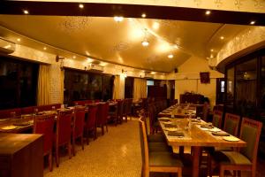 una sala da pranzo con tavoli e sedie in legno di Nirali Resorts a Rajkot